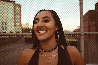 Smiling woman with braids in urban setting at sunset
