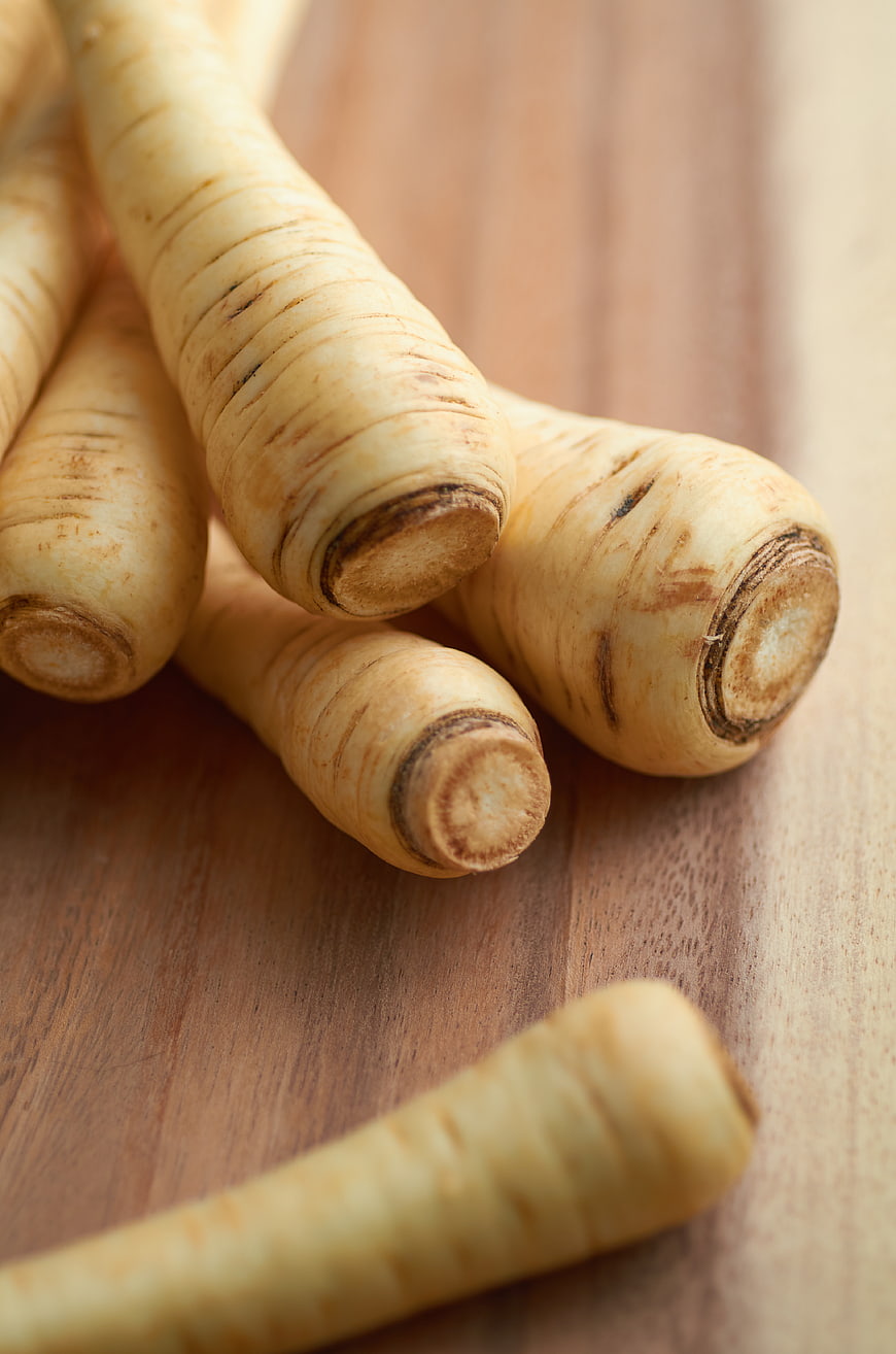 Fresh parsnips on wooden cutting board close up