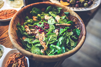 Fresh spinach chicken salad with pomegranate seeds in wooden bowl