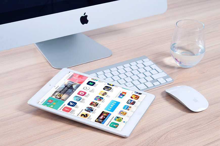 Modern workspace with iPad, Mac, keyboard, and water glass