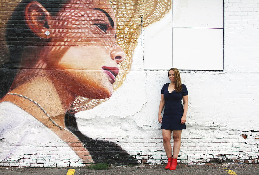 Woman in Navy Dress and Red Boots Standing by Street Art Mural