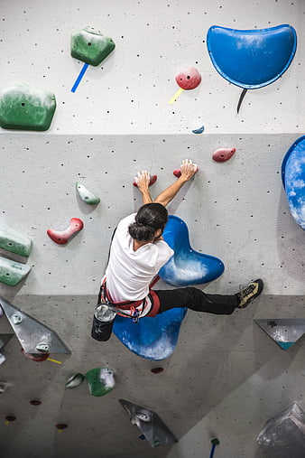 Man climbing indoor rock wall with colorful holds