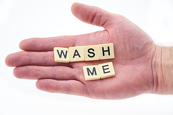 Hand holding Scrabble tiles spelling wash me