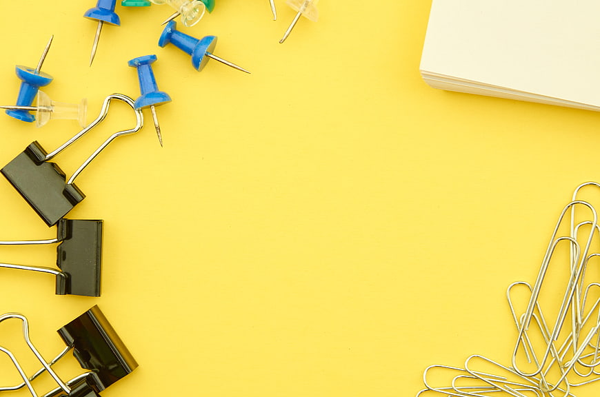 Flat lay of office supplies on yellow background with copyspace