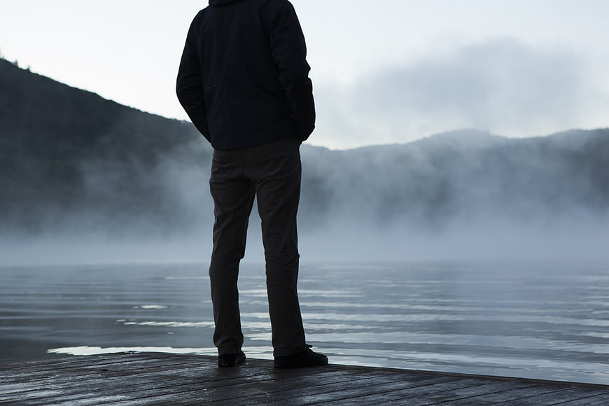 Man Standing on Wooden Dock Overlooking Misty Lake