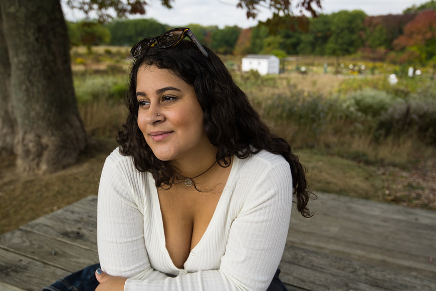 Smiling Brunette Woman in White Top Sitting on Wooden Deck