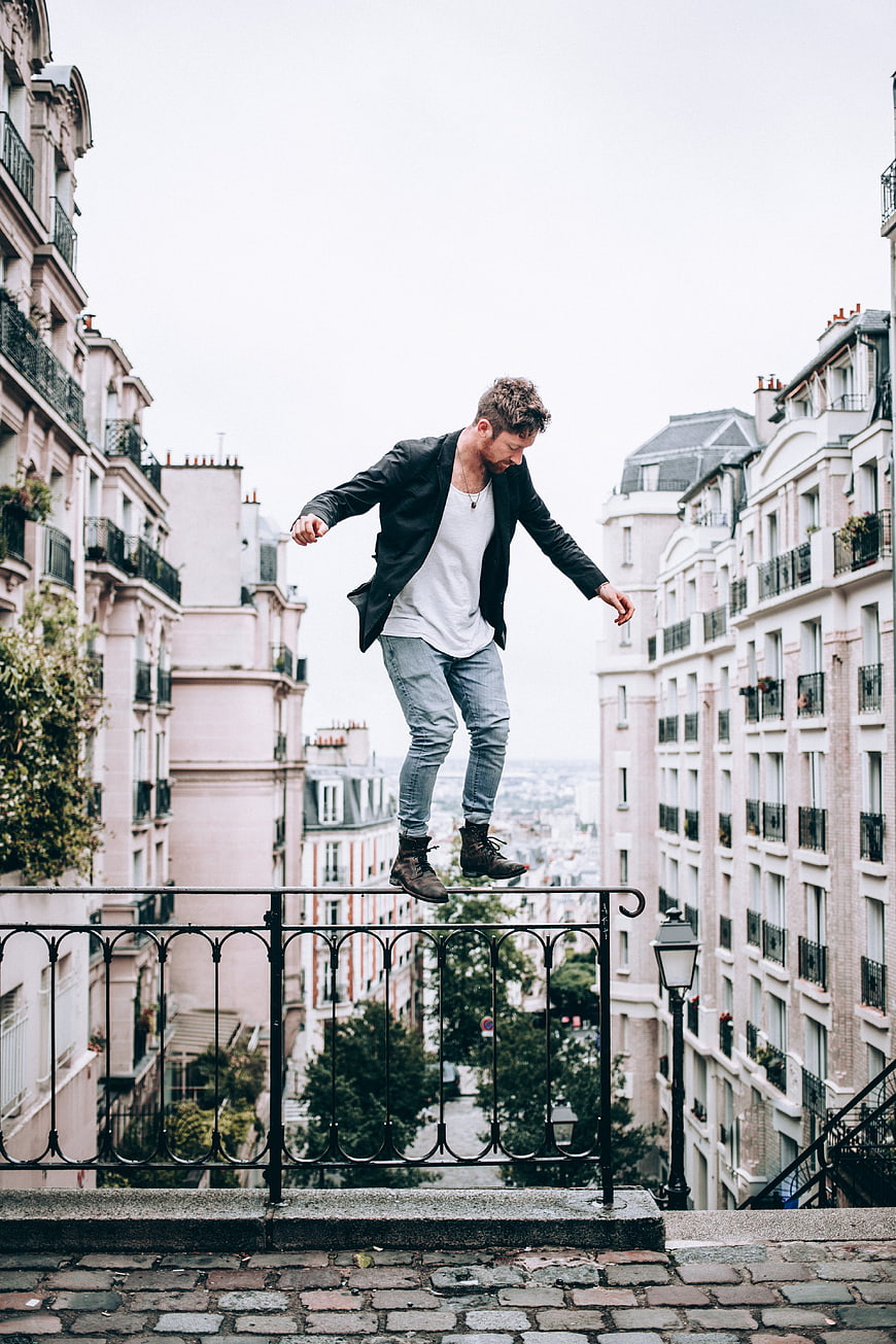 Man balancing on railing in Parisian urban setting
