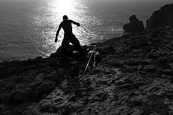 Silhouette of Fisherman Casting Rod on Rocky Coast
