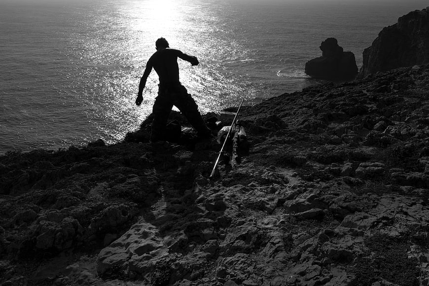 Silhouette of Fisherman Casting Rod on Rocky Coast