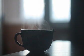 Silhouette of Steaming Coffee Cup on Table by Window