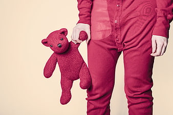 Child in red onesie holding matching knitted teddy bear
