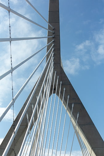 Low angle view of modern cable-stayed bridge tower against blue sky