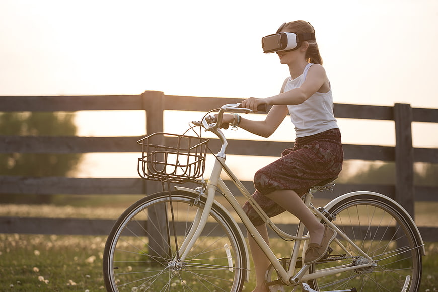 Girl Riding Bicycle with VR Headset in Field
