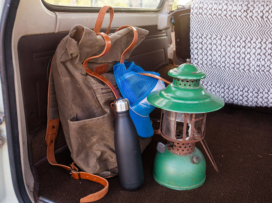 Vintage camping gear in car trunk with backpack and lantern