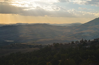 Golden hour sun rays over rolling hills and valley landscape