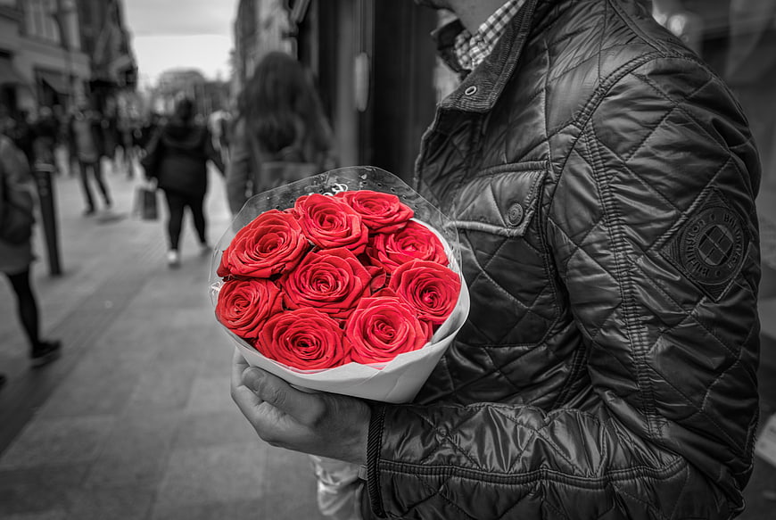Man holding bouquet of red roses on city street