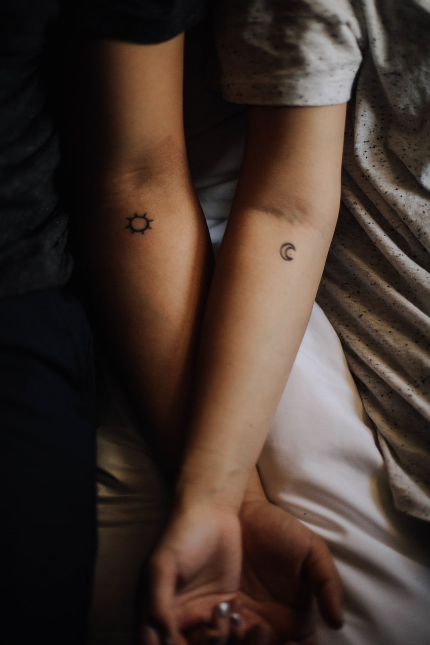 Couple with matching sun and moon tattoos on forearms