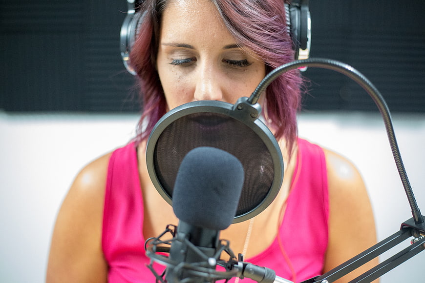 Woman with purple hair recording in studio with microphone