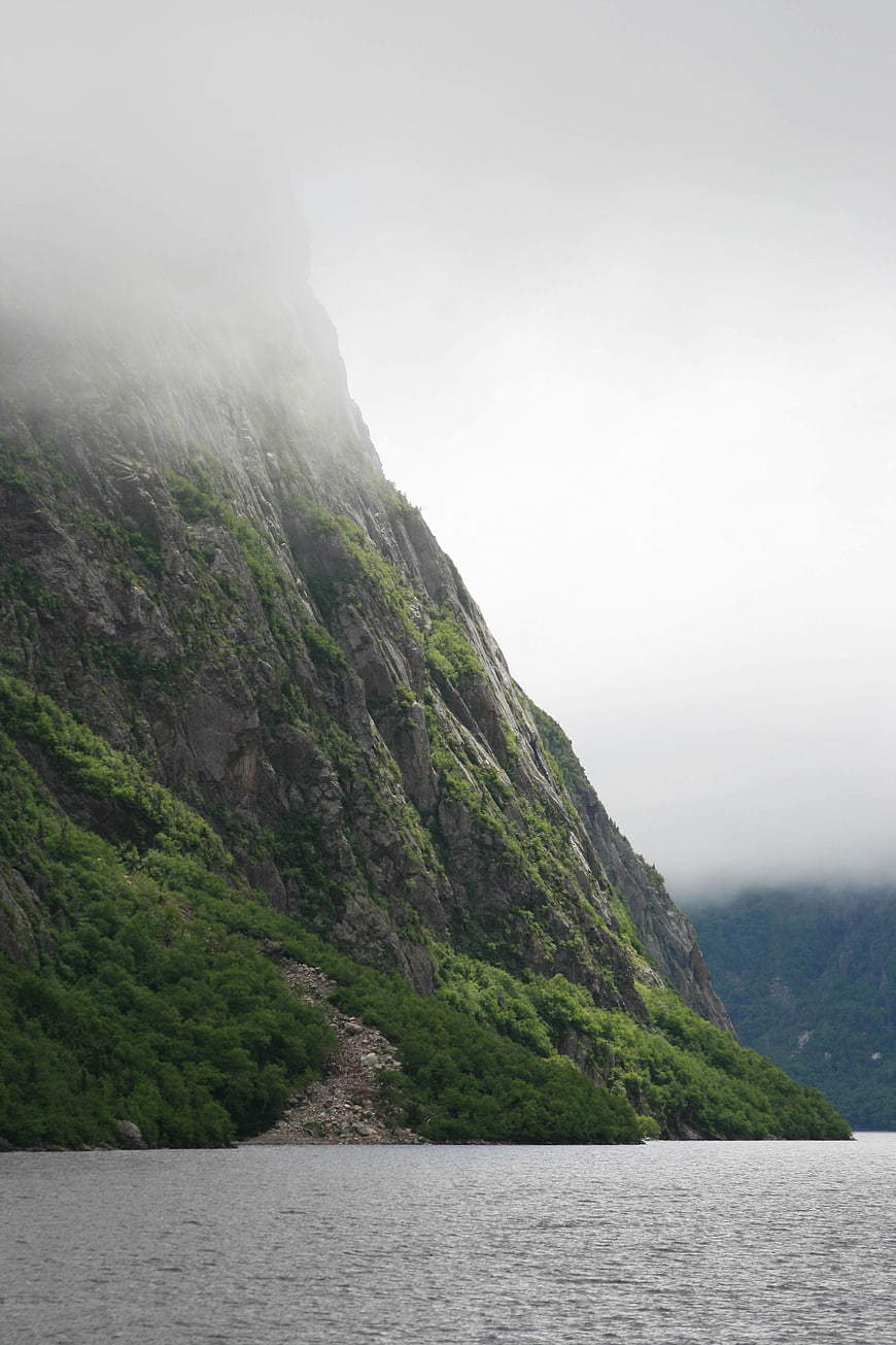 Misty Mountain Cliff Overlooking Calm Fjord Water