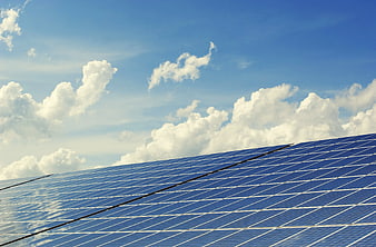 Blue Solar Panels Against Blue Sky with White Clouds