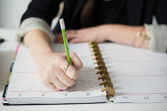 Woman Writing in Planner with Green Pencil