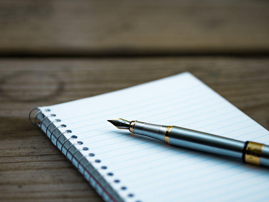 Silver fountain pen on lined notebook page