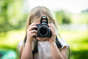 Young girl holding DSLR camera in garden