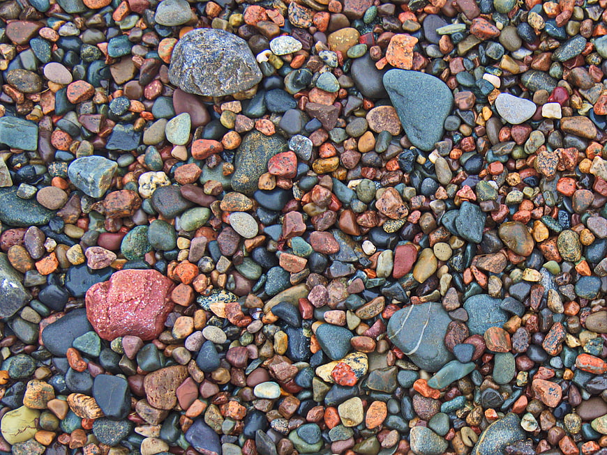 Colorful wet pebbles and stones on a beach shore texture