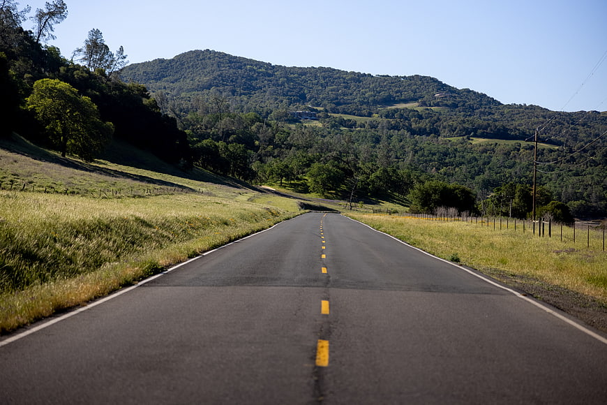 Empty asphalt road winding through green hills and mountains