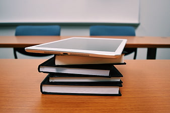 White Tablet on Stack of Books in Classroom