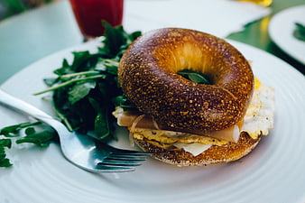 Delicious Bagel Sandwich with Eggs and Salad on White Plate