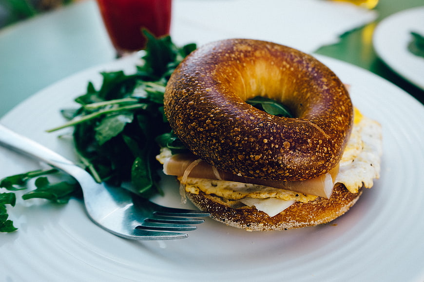 Delicious Bagel Sandwich with Eggs and Salad on White Plate