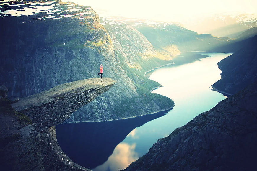 Woman doing yoga on Trolltunga rock formation in Norway