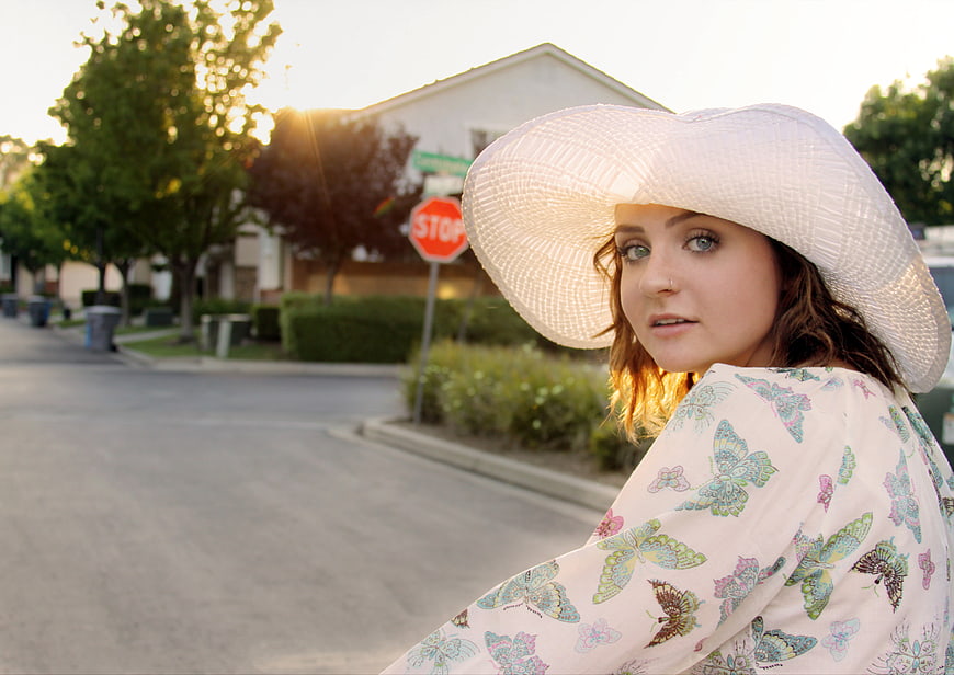 Woman in White Hat and Butterfly Shirt on Suburban Street