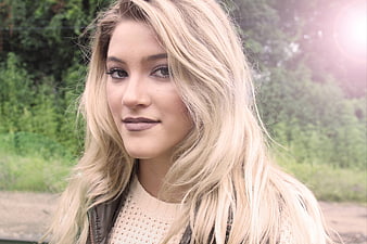 Portrait of a smiling blonde woman outdoors with lens flare
