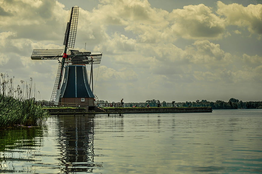 Traditional Dutch Windmill by Lake with Cloudy Sky