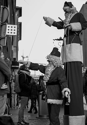 Black and white photo of Santa Claus on stilts entertaining children