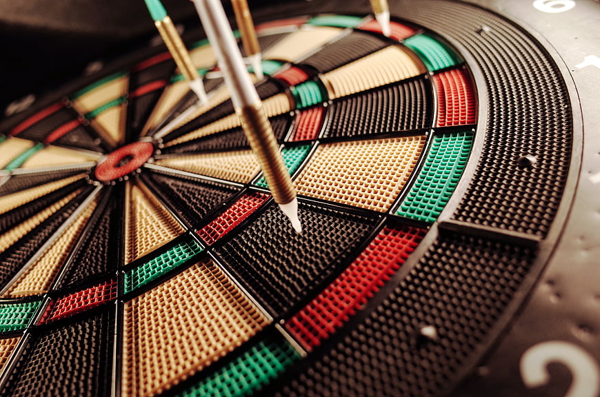 Close-up of darts hitting a dartboard target