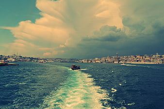 Boat wake on Bosphorus strait with Istanbul skyline and dramatic clouds