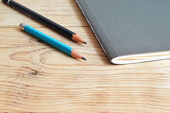 Two Pencils and Notebook on Wooden Desk