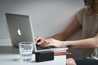 Woman Typing on Laptop with Glass of Water
