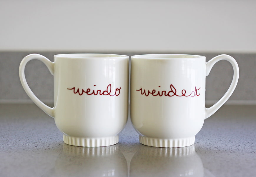 Two white mugs with red text 'weirdo' and 'weirdest'