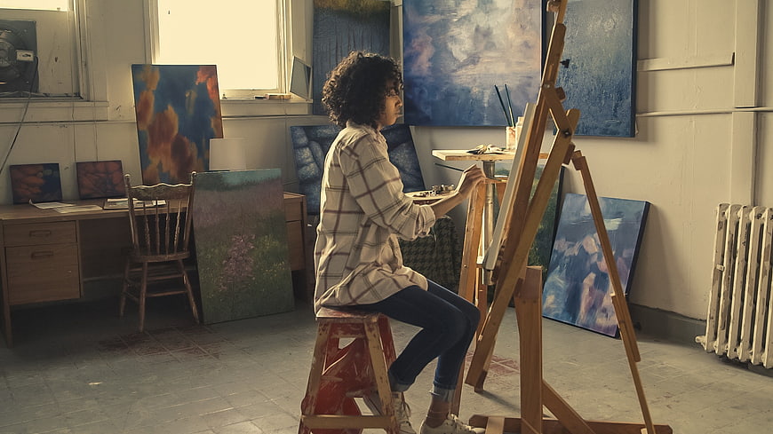 Female artist painting in a sunlit studio with easel