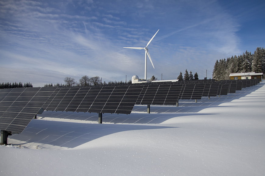 Solar panels and wind turbine in snowy winter landscape