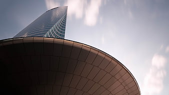 Low angle view of modern glass skyscraper and curved building