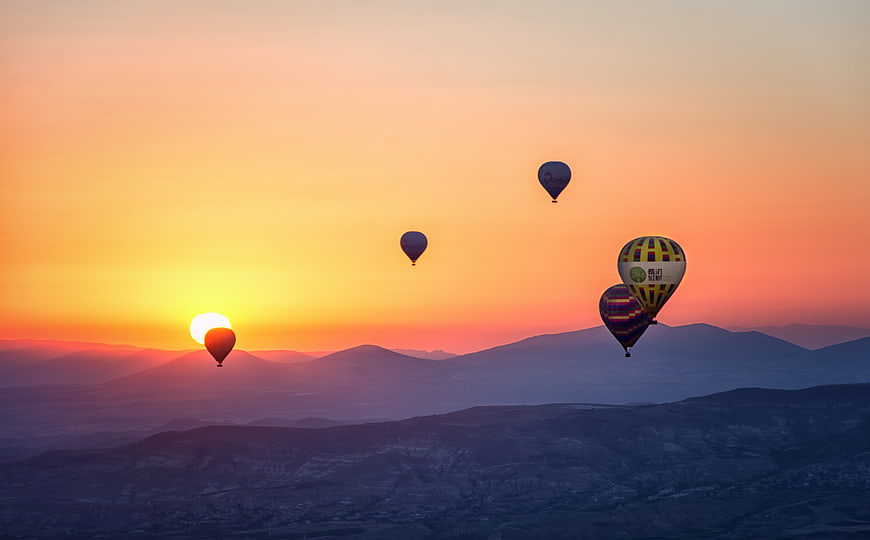 Hot Air Balloons Flying Over Mountains at Sunrise