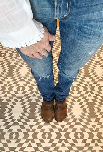 High angle view of woman in jeans and boots on patterned floor