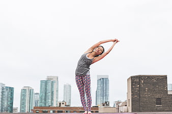 Woman stretching on rooftop with city skyline background