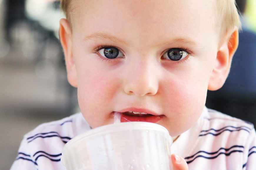 Close-up of cute toddler boy drinking from plastic cup