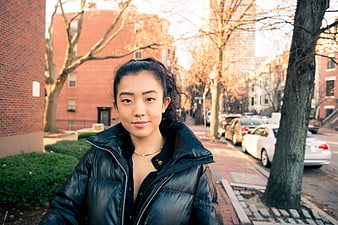 Asian woman in black puffer jacket on city street